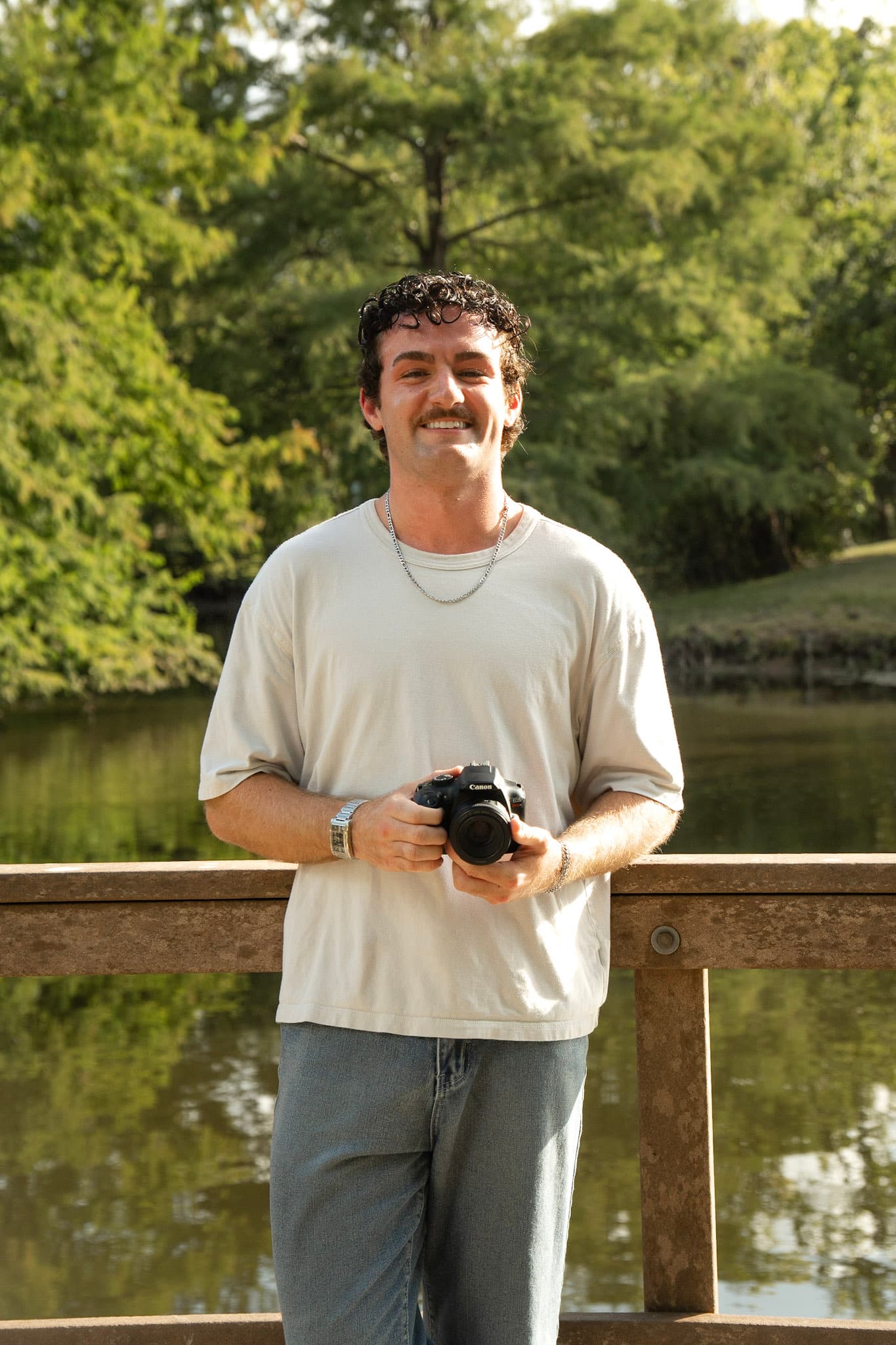 Garrett Walthall standing at a campus railing, camera in hand